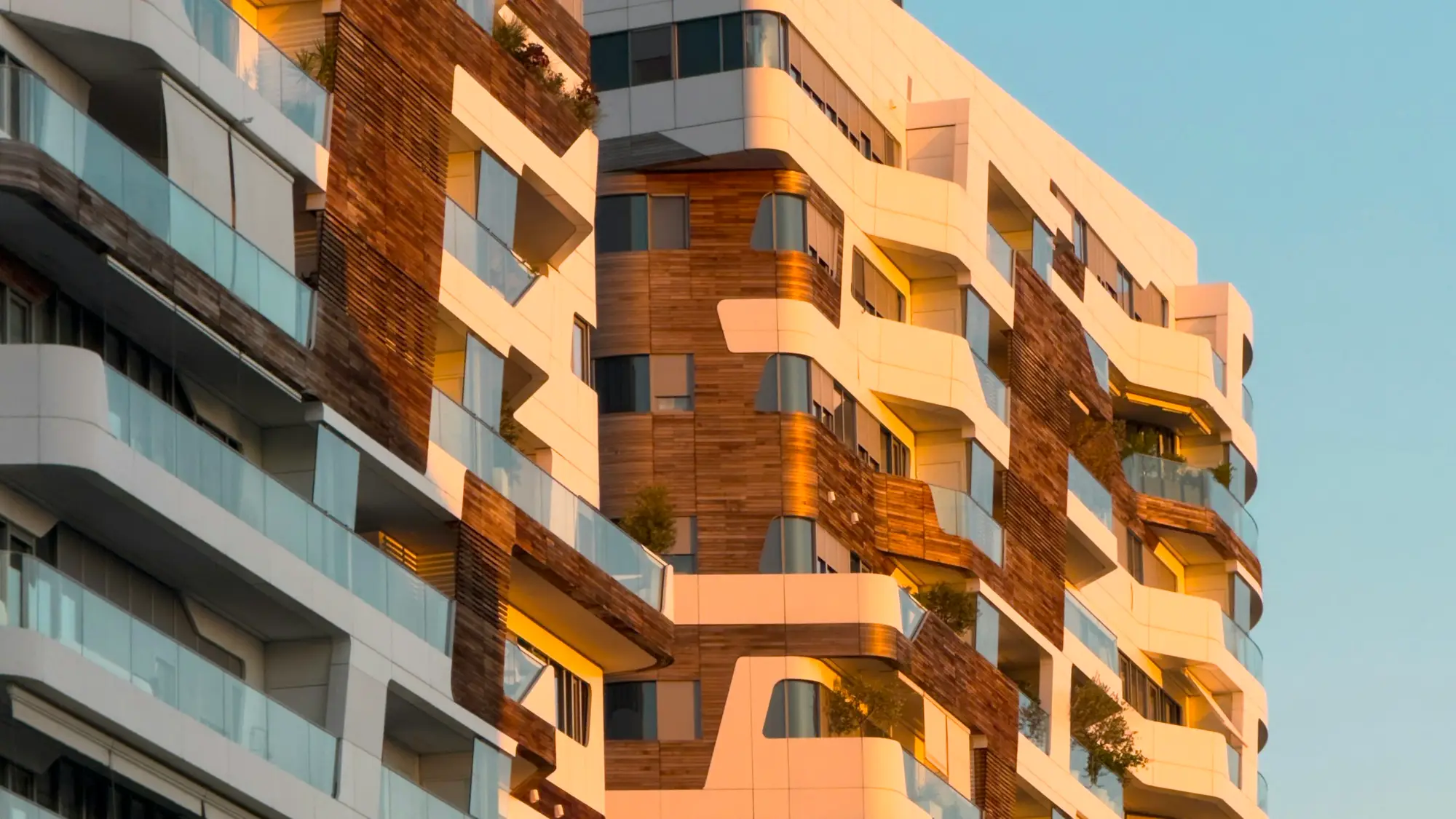 Façade d’un immeuble de logements contemporain, balcons de bois baignés d’une lumière dorée