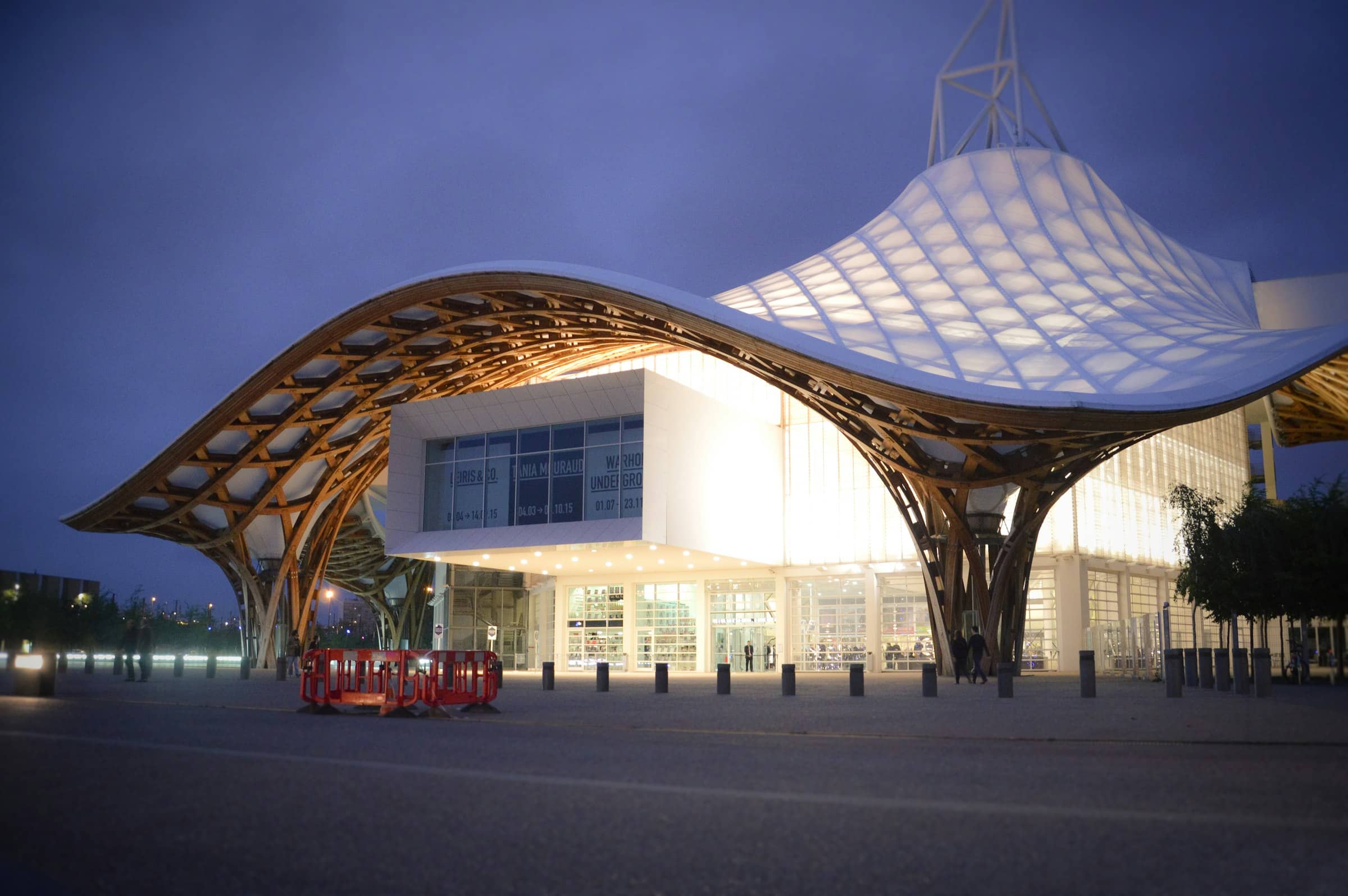 Bâtiment public contemporain à la toiture blanche, vu depuis son esplanade