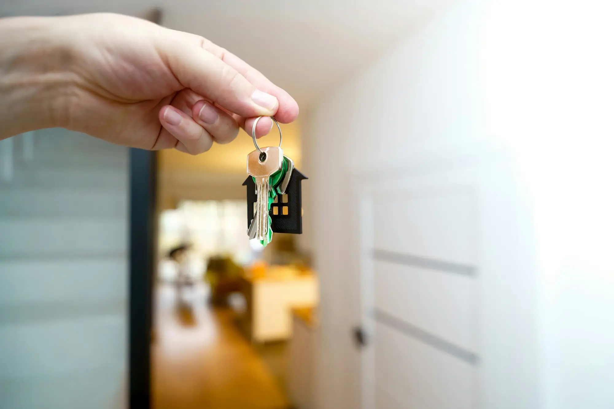 Trousseau de clés tendu devant la porte claire d’un logement