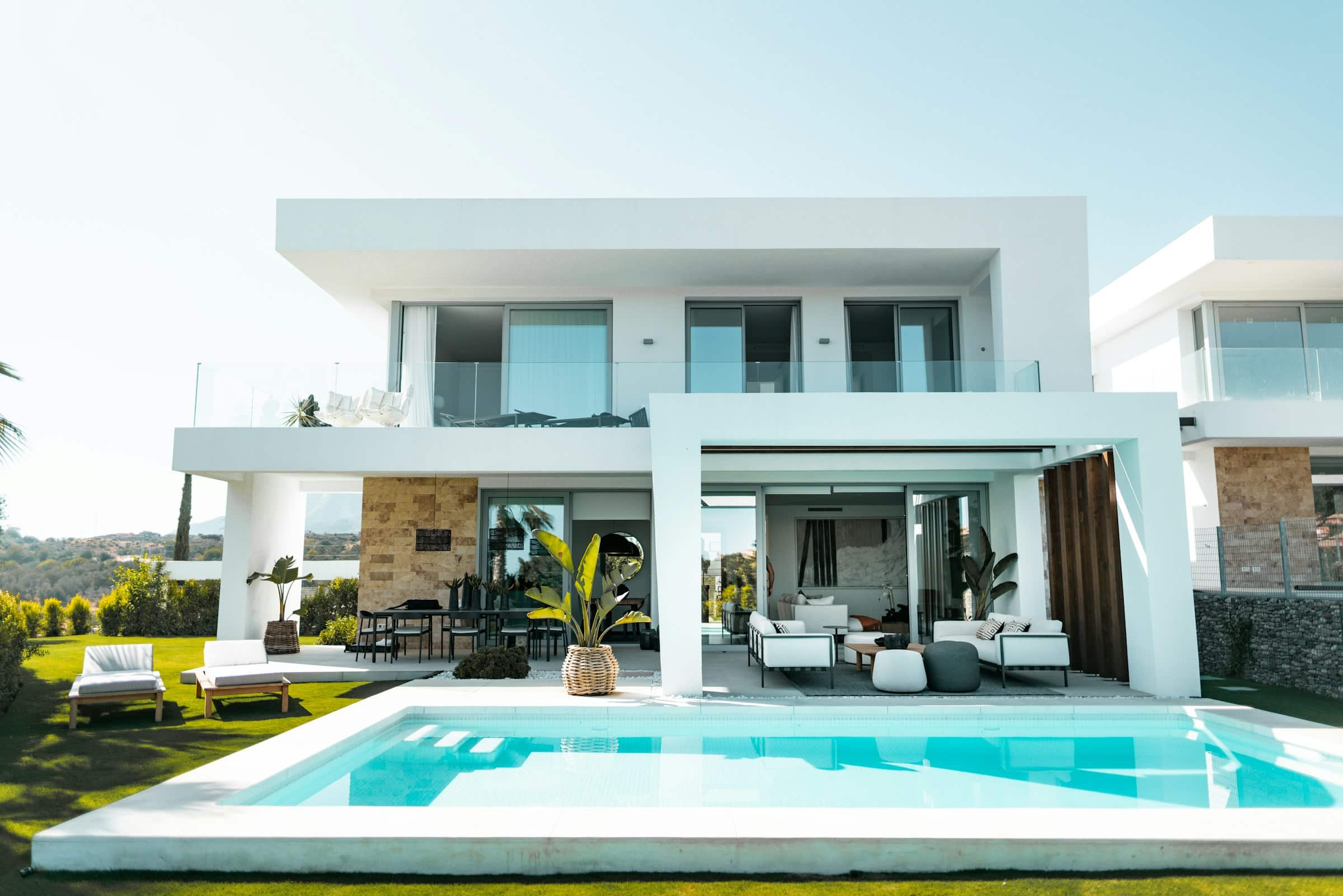 Villa contemporaine blanche aux grandes baies vitrées, au bord de sa piscine