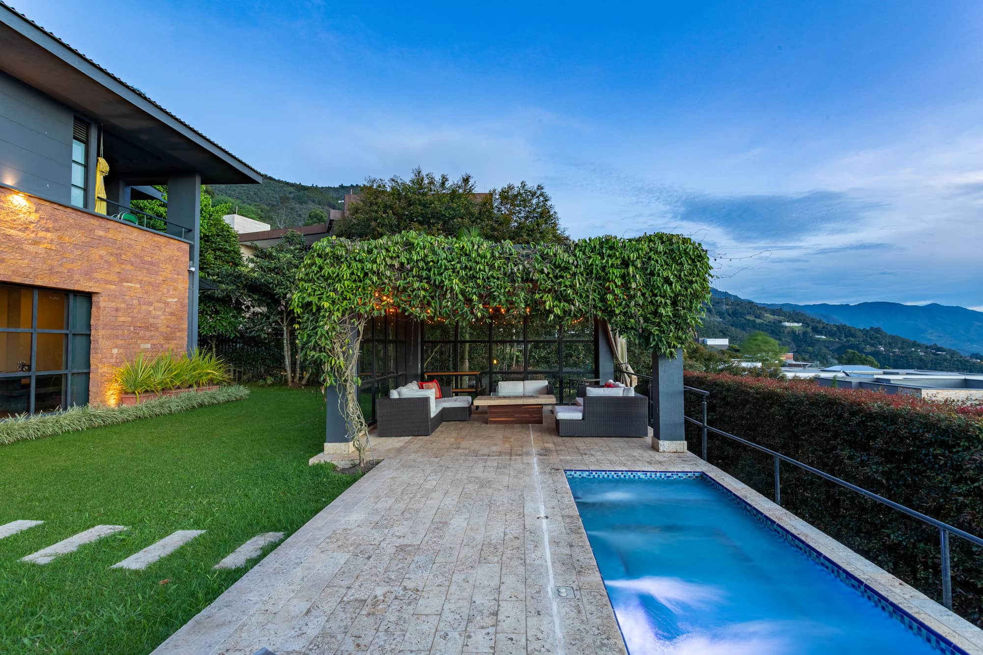 Villa du sud et sa piscine, pergola de bois couverte de végétation face aux collines